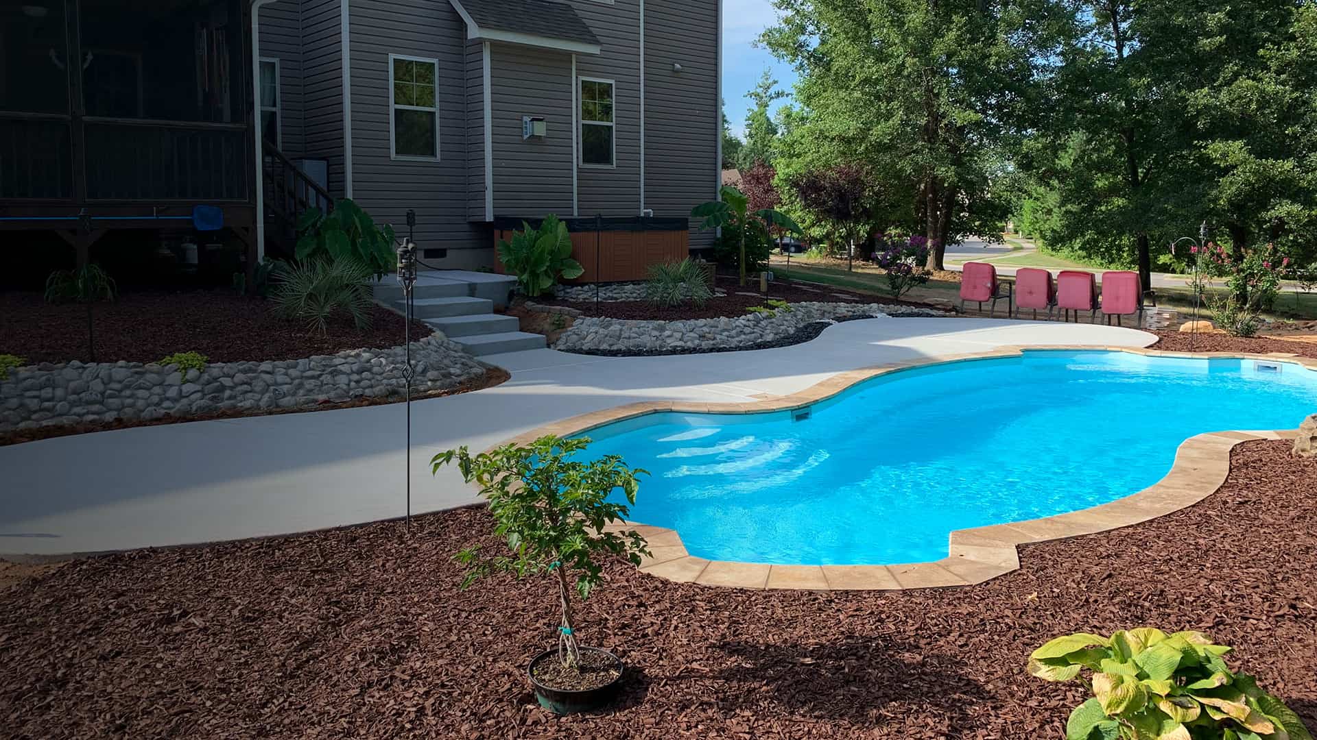 inground fiberglass pool with beautiful backyard landscaping