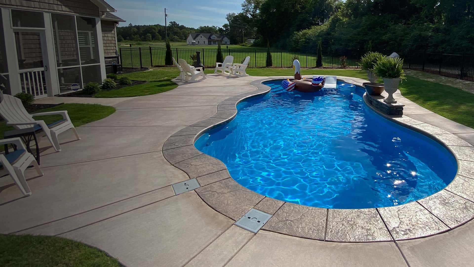 inground fiberglass pool with eagle float and lush landscaping